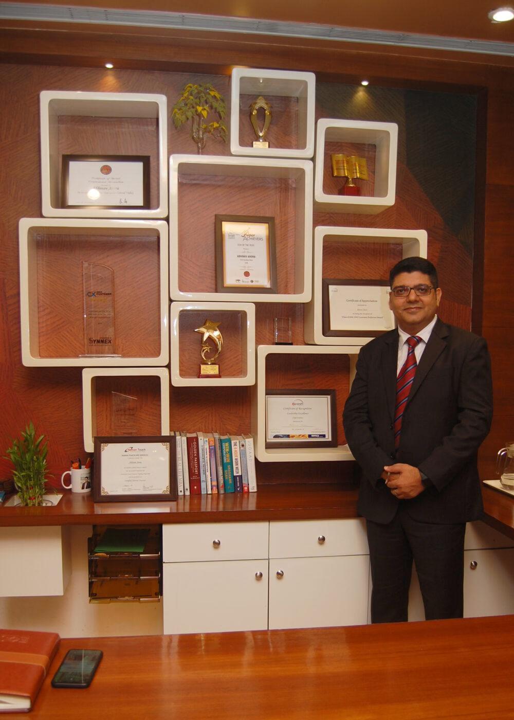 A man in a suit standing beside an office wall covered with framed awards A man in a suit standing beside an office wall covered with framed awards